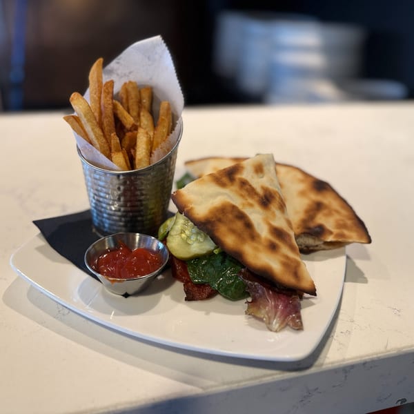 A Mikas Neapolitan Pizza sandwich with fries and ketchup on a white plate.